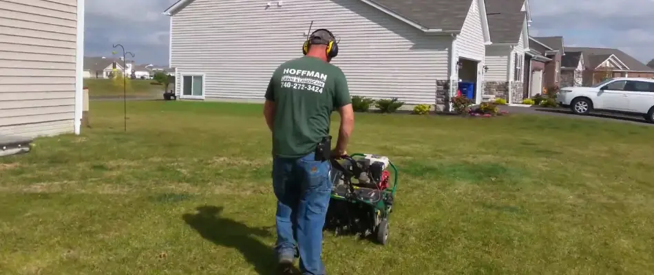 Crew pushing an aerator machine across a lawn in Delaware, OH.