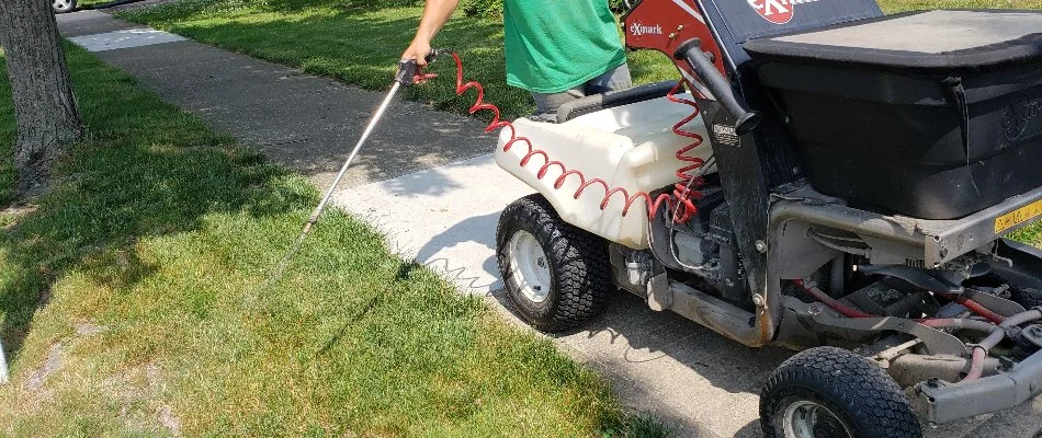 Lawn care professional applying a liquid weed control treatment on a lawn in Delaware, OH.