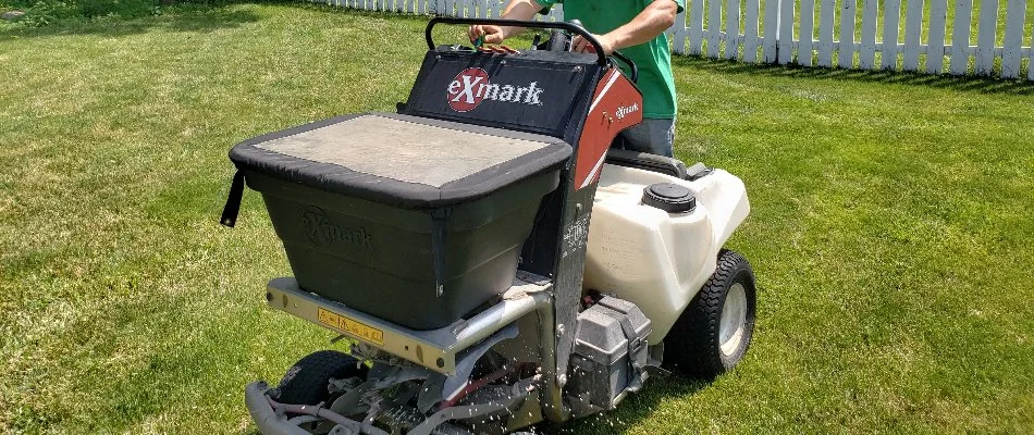 A professional applying a fertilizer treatment to a lawn in Delaware, OH, during the spring.