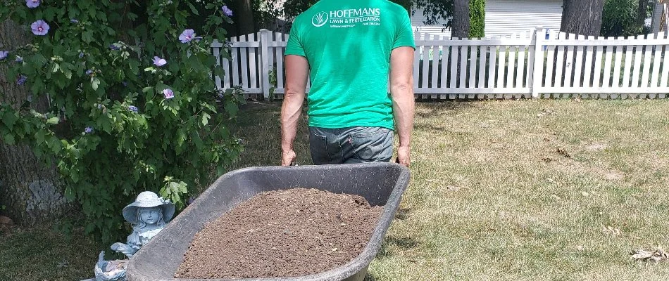 Worker pulling wheelbarrow with mulch in Delaware, OH.