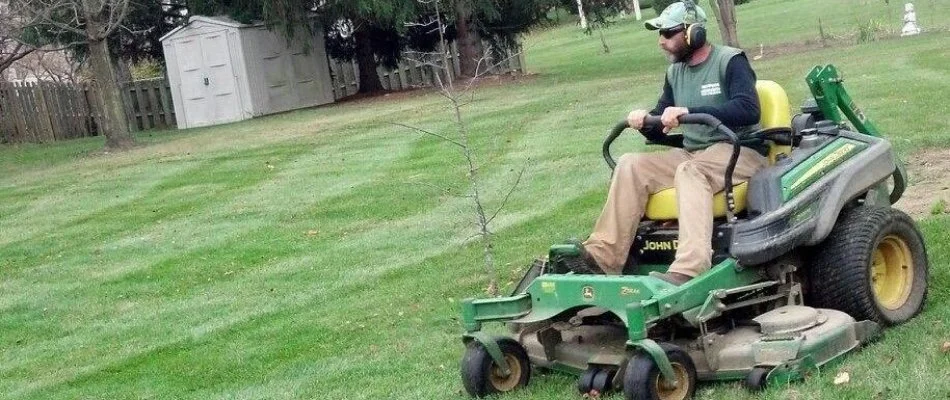 Crew member wearing a hat while mowing a lawn on a property in Delaware, OH.
