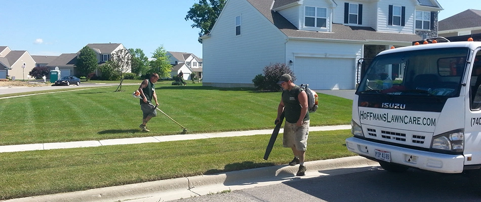 Technicians blowing and string trimming lawn in Delaware, OH.